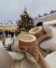 a person holding up some bread in front of a christmas tree with lights on it