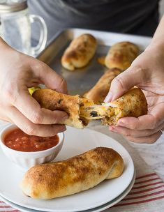 someone is dipping some food into a small white bowl on a plate with sauce and bread