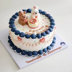 two teddy bears sitting on top of a birthday cake