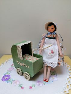 a doll is standing next to a toy carriage