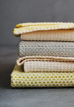 four pieces of knitted fabric stacked on top of each other in different colors and patterns