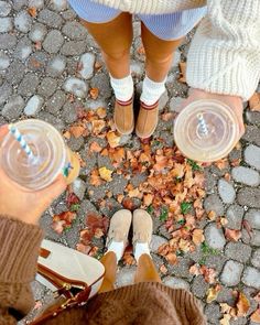 two people standing next to each other with their feet on the ground and holding cups