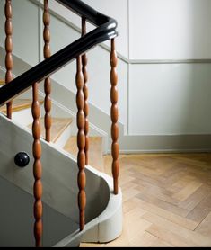 a wooden stair case next to a handrail in a room with white walls and wood floors