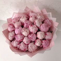 a bouquet of pink flowers sitting on top of a white table next to a wall