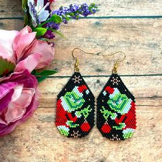 a pair of black and red beaded earrings sitting on top of a wooden table