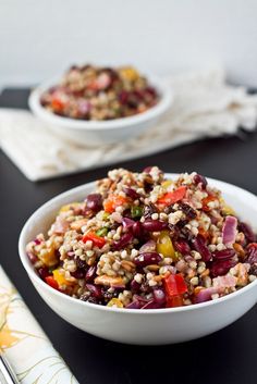 two bowls filled with food sitting on top of a black table next to silverware