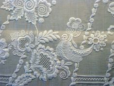 an embroidered fabric with white flowers and birds on it, as well as other decorative items