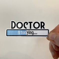 a person holding up a sticker with the word doctor studying in black and white