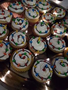 cupcakes with white frosting and colorful icing are arranged on a silver platter