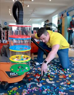 a man is bending over to pick up some toys in a room with lots of confetti on the floor