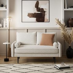 a living room with a white couch and some books on the shelf next to it