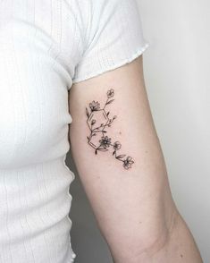 a woman's arm with a small flower tattoo on the left side of her arm