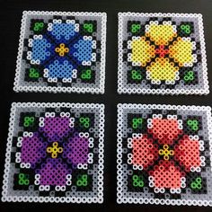 four squares with flowers made out of perler beads on top of a black table