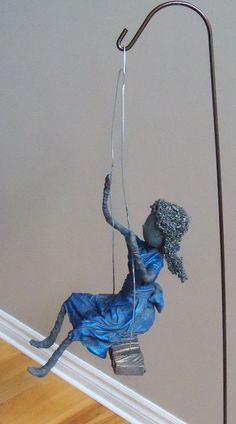 a statue is hanging from a pole on the floor in front of a wall and hardwood floor