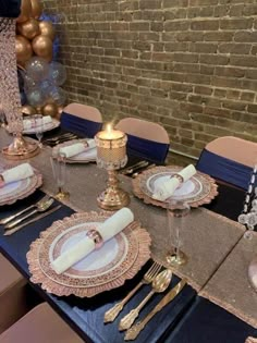 the table is set with gold and white plates, silverware, and napkins