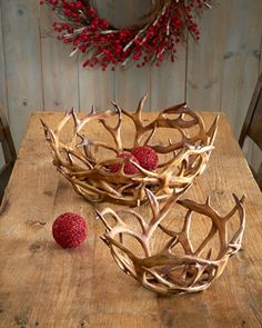 a wooden table topped with antlers and raspberries next to a red berry wreath