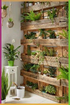 a wooden pallet filled with potted plants on top of a white table next to a green wall