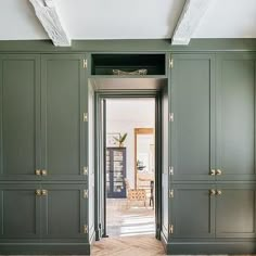 an empty room with green cupboards and wood flooring on the side walk way