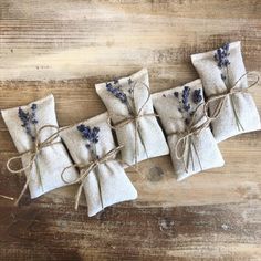 four small lavender sacs tied with twine on a wooden table, ready to be used as favors