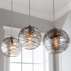 three lights hanging from a ceiling in front of a window