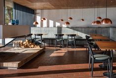 an empty restaurant with wooden tables, chairs and lights hanging from the ceiling above them