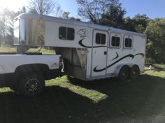 a white horse trailer parked on top of a lush green field