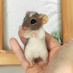 a hand holding a small toy mouse in it's right hand, next to a mirror