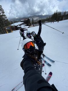 two skiers pose for the camera on a snowy mountain slope with their arms in the air