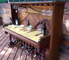 a wooden table with wine glasses and bottles on it next to a fenced in area