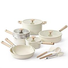 a set of white pots and pans with wooden spoons next to each other