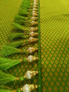 green and yellow fabric with white beads on it's ends, along with gold trim