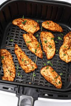 chicken skewers are cooking on the grill in an air fryer with green garnishes