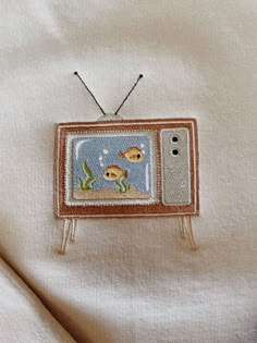 an old television with fish on it is sitting on a white cloth covered bed sheet