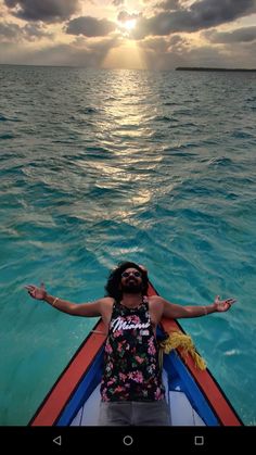 a person sitting in a boat on the water with their arms out to the side