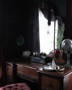 a desk with a mirror, lamp and other items on top of it in front of a window