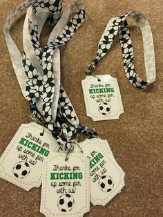 some tags with soccer balls on them are hanging from a ribbon that says thanks for kicking