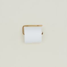 a roll of toilet paper sitting on top of a white wall next to a gold handle