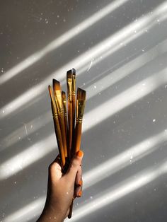 a hand holding up some gold colored objects in front of a window with white light streaming through it