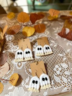 some little decorations made to look like ghost faces are on a doily with leaves