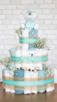 a baby shower cake with a teddy bear on top and blue ribbon around the bottom