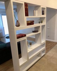 a white book shelf with books and other items on it's shelves in a living room