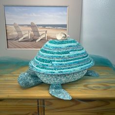 🐢 HANDMADE COILED ROPE SEA TURTLE BASKET WITH LID  | BEACH THEME STORAGE SOLUTION 🌊 This is a handmade turtle basket with lid.  The bottom of tropical coiled rope basket is made with a blue and white fabric that has metallic silver sprinkles throughout.  The legs and head are made from a light blue shimmery fabric to compliment the top which is made with a variety of blue and teal fabrics. Inside the bottom is a coral fabric.  As a beach theme storage bin, this adorable turtle, as a table cent Nautical Basket, Coiled Rope Basket, Silver Sprinkles, Turtle Shape, Essential Office Supplies, Shimmery Fabric, Storage Baskets With Lids, Coffee Pod Holder, Coiled Rope