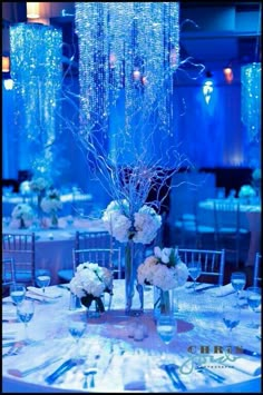 the centerpieces are decorated with white flowers and blue lights