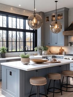 a kitchen island with stools in front of it and three hanging lights above it