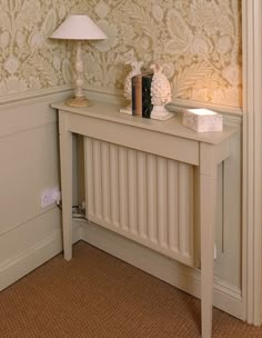 a white table with a lamp on top of it next to a wallpapered wall