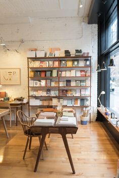 a room filled with lots of books on shelves next to a wooden table and chairs