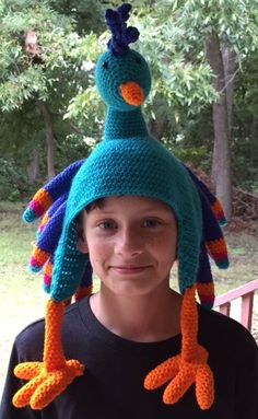 a young boy wearing a crocheted hat with an orange and blue bird on it