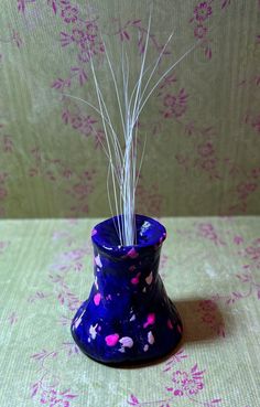 a blue vase with pink and white splatkles on it sitting on a table