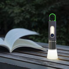 an open book sitting on top of a wooden table next to a light that is turned on