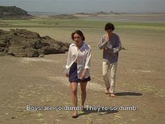 two people walking across a sandy beach next to the ocean with words written on them